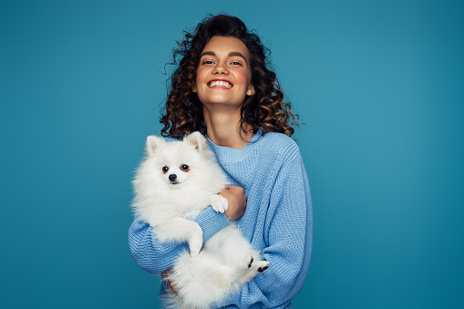 Studio portrait of smiling young woman holding little dog