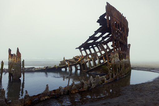 The wreckage of the ship Peter Iredale on the Pacific coast of Oregon, United States.  The fog of the morning makes for an eerie scene.