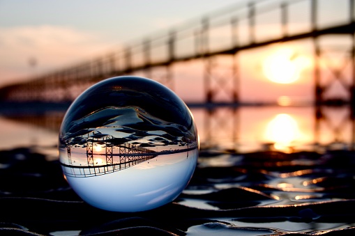 Crystal ball and pier at sea during sunrise
