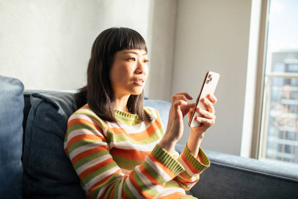 istock Young Japanese Woman using a smart phone at home 1498729868