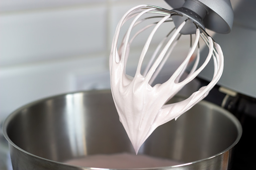 Stainless steel pot and whisk with whipped cream close-up