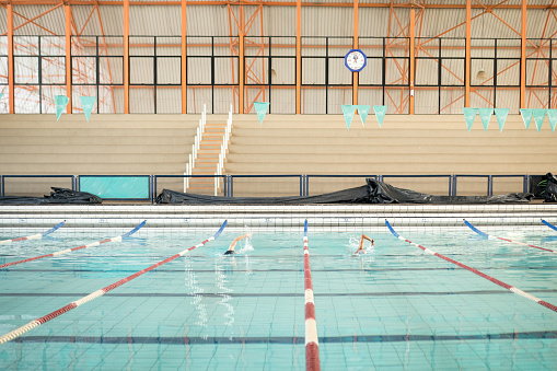 partially blurred interior of an indoor sports pool with a row of diving boards