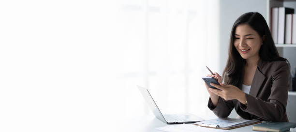 istock Young charming businesswoman using smartphone while working on laptop computer in office room. 1498731243