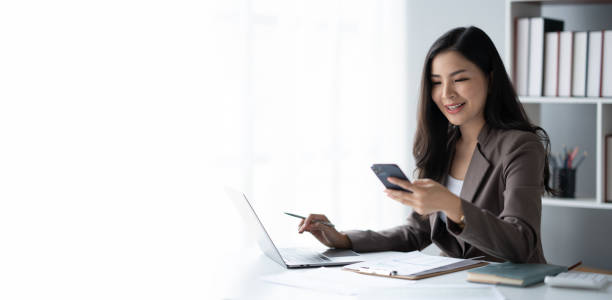 istock Young charming businesswoman using smartphone while working on laptop computer in office room. 1498731485