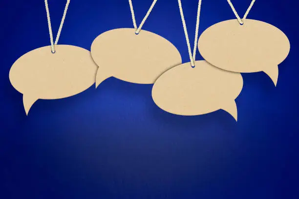 Photo of empty speech bubbles hanging on a thread on a blue background