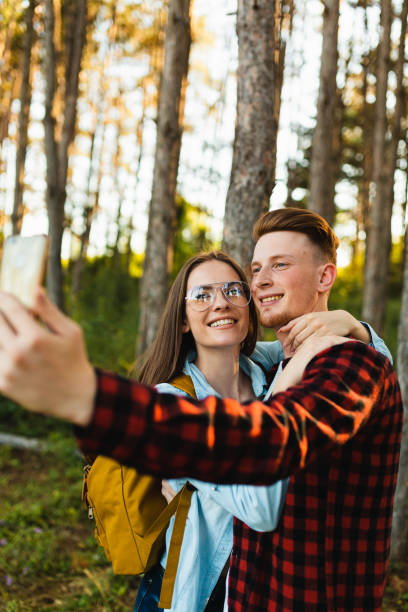 istock couple having fun taking selfie with mobile phone in the forest 1498738206