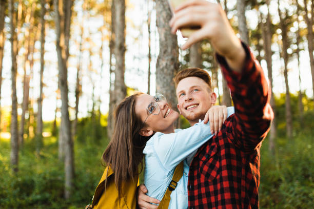 istock couple having fun taking selfie with mobile phone in the forest 1498738242