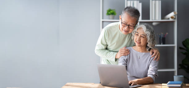 istock Mature old couple spending their time together using laptop computer, having a great time in the living room. 1498740625