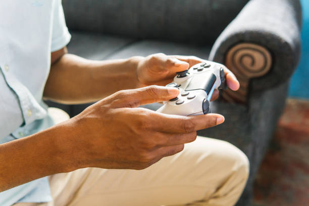 Hands using a joystick to play a videogame at home.