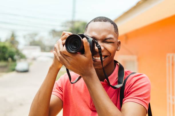 istock Young stylish male photographer using camera while exploring the city 1498743224