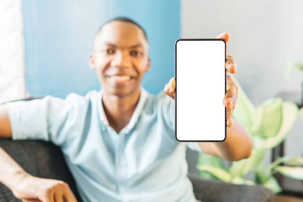 istock smiling man showing mobile phone blank white screen mockup to camera. 1498743252