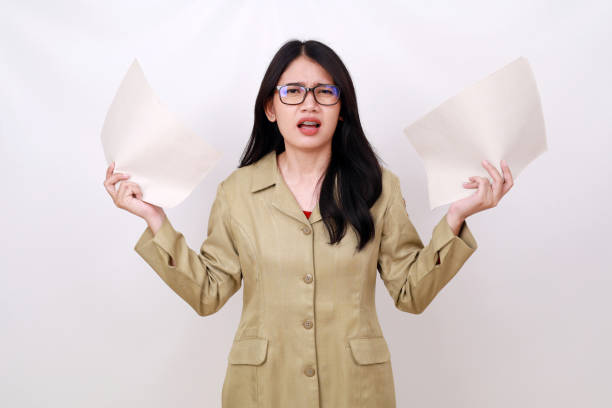 istock Confused young teacher standing while holding paper with frustrated face expression 1498745898
