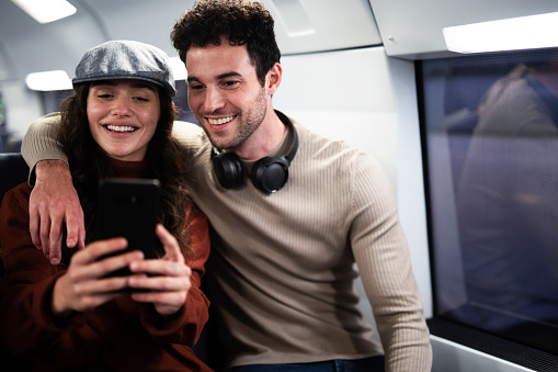 Loving couple travel by train. Happy woman and man talking while sitting in the train.