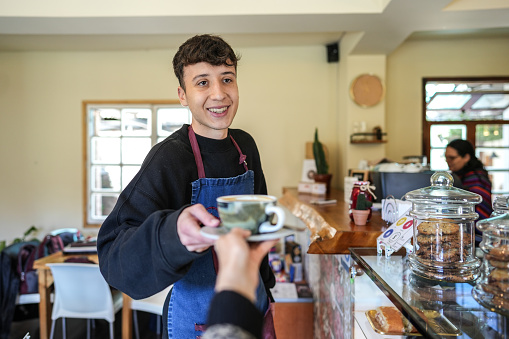 Waiter serving a cup coffee at a coffee shop