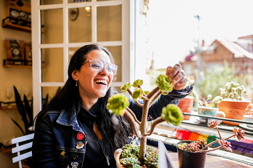Mid adult woman caring of plants at a coffee shop