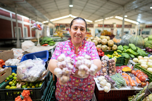 Portrait of a senior female customer or seller holding a garlic in the supermarket