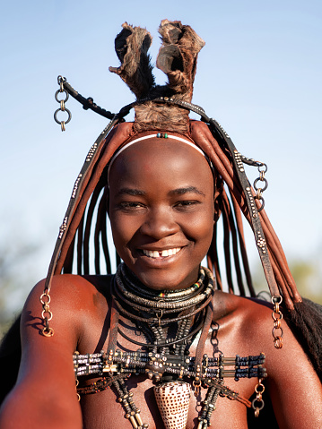 Cheerful Himba woman smiling, dressed in traditional style at her village in Namibia, Africa.