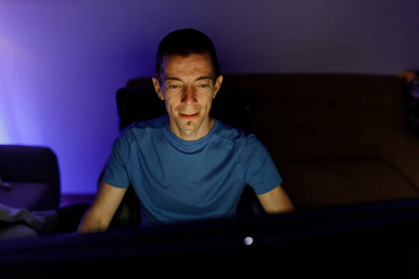 istock Mature man playing online games on his computer at night in neon lighting room 1498758881