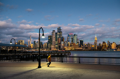 Teenager running in Hoboken by New York City skyline at dusk