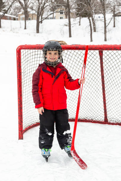 garçon avec un bâton de hockey souriant à la caméra - ice hockey child childhood little boys photos et images de collection