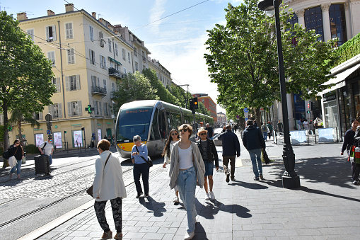 Avenue Jean Medecin In Nice French Riviera France Europe, Retail Store, Building Exterior, Tree, People Waiting For Public Transportation Tram, Walking Back And Forth Scene During Springtime