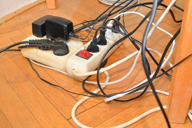 Tangled cables in the extension cord. Messy cables. Cables tangled on parquet flooring. stock photo