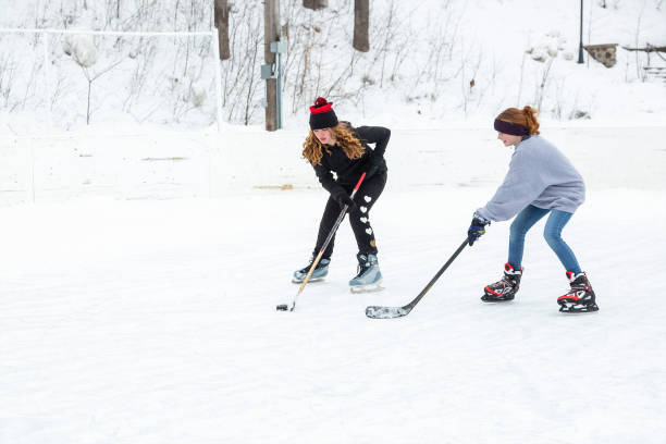 zwei mädchen, die im winter eishockey spielen - ice skating ice hockey child family stock-fotos und bilder