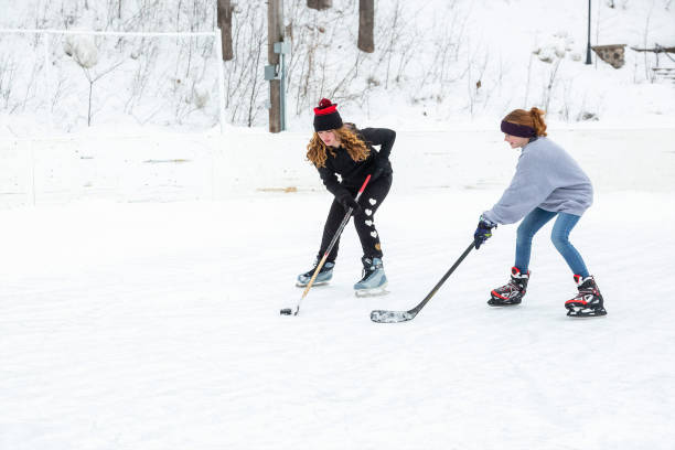 dos niñas jugando hockey sobre hielo en invierno - ice skating ice hockey child family fotografías e imágenes de stock