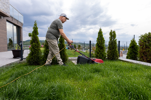 Senior man cutting grass with a lawnmower