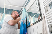Balding Male Looking At Reflection In Mirror While Trimming Moustache