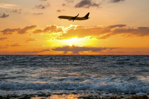 istock Plane flying over sea during sunset. Sun shining through clouds 1498772442