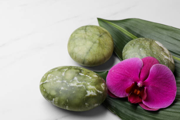 istock Beautiful spa composition with stones, flower and leaves on white marble table, closeup 1498772565