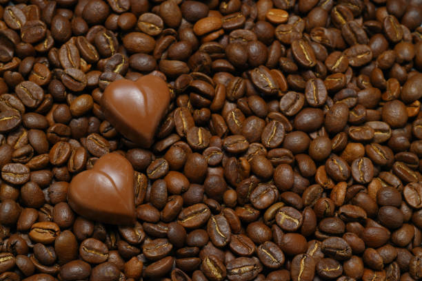 Tiny chocolate in heart shape on coffee beans. Close up.
