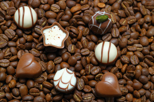 Tiny chocolate in heart shape on coffee beans. Close up.