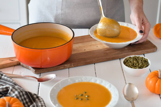 istock Woman using ladle to pour pumpkin soup into bowls in a kitchen 1498775233