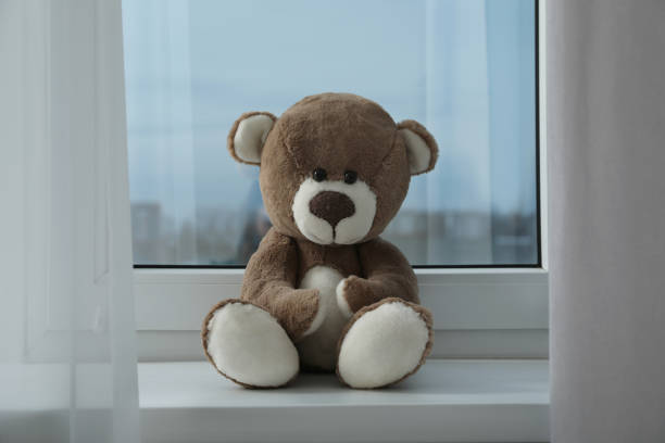 istock Cute lonely teddy bear on windowsill indoors 1498775415