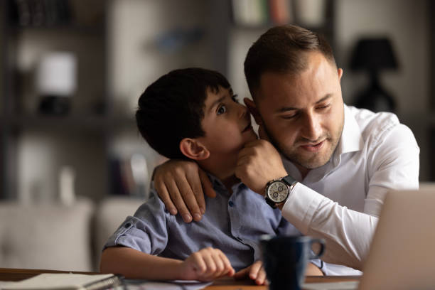 istock Little Boy whispers in ear confides a secret to daddy 1498776945
