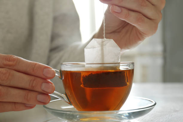 mujer sacando una bolsa de té de la taza en la mesa en el interior, primer plano - tea drink cup afternoon tea fotografías e imágenes de stock