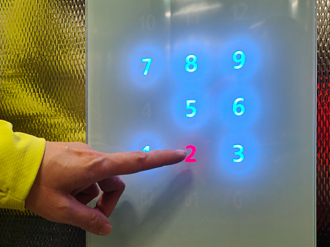 An Asian woman is pressing touch screen elevator panel