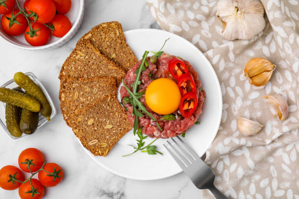 saboroso steak tartare de carne servido com gema e outros acompanhamentos sobre mesa de mármore branco, flat lay - accompaniments - fotografias e filmes do acervo