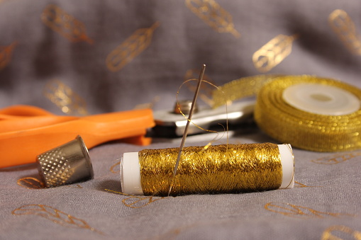 Spool of Metallic Gold Thread on Gray and Gold Fabric