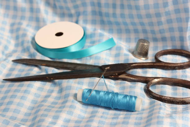 Spool of Blue Thread, Thimble and Needle on Vintage Blue and White Fabric