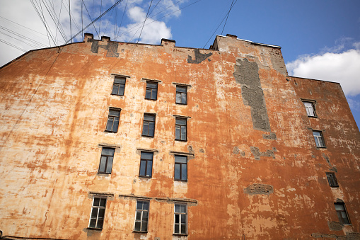 View of old multi-story building with yellow stucco wall and windows, blue sky