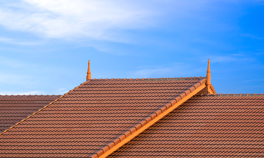 2 levels of Brown ceramic tile roof in vintage style against blue sky background
