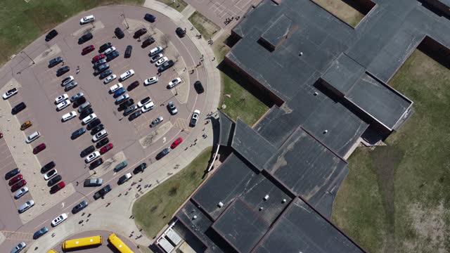 Drone overhead aerial view of a school letting out students at the end of the day.