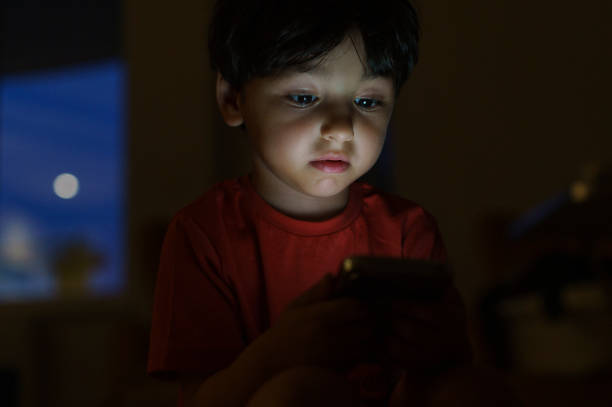 istock Cute little boy playing with a smartphone at night 1498795497