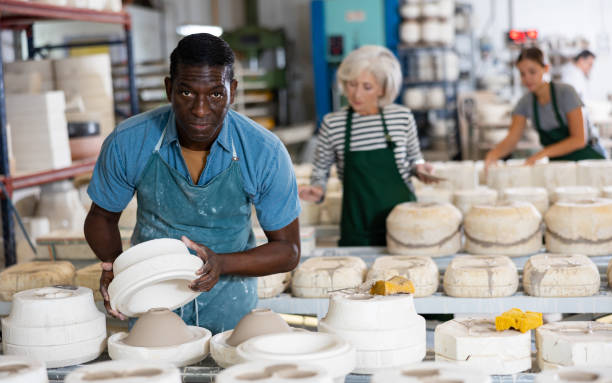 Man ceramist working in pottery workshop African-american man ceramist in apron crafring new ceramic bowl in workshop. kenyan man stock pictures, royalty-free photos & images