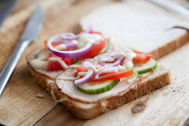 A close up shot of a sliced meat sandwich being prepped in a kitchen