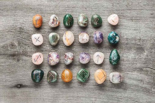 Elder Futhark Rune Stones Set Made of Natural Gemstones on Wooden Background