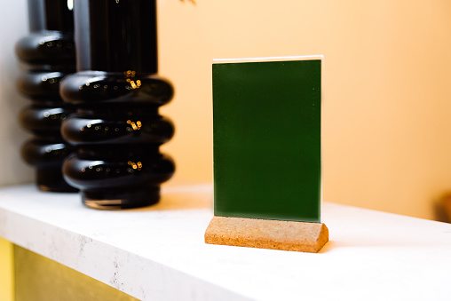 the green table tent on a cork footboard stands on the bar in the foreground from the black vases